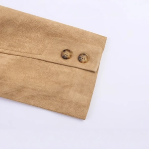 Macro shot of a tan faux suede coat cuff featuring two dark tortoiseshell buttons