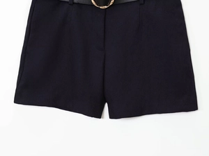 Détail du short bleu foncé avec ceinture en cuir noir et boucle ronde en métal doré