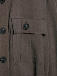 Gros plan sur une chemise marron avec poche à rabat et boutons ronds noirs de qualité