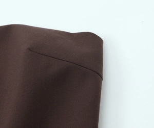 Gros plan des coutures fines et du tissu tissé sur un haut bustier marron foncé
