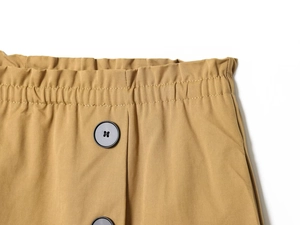 Dettaglio dei pantaloncini kaki a vita alta con elastico in vita e bottoni neri