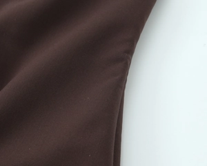 Gros plan sur la texture du tissu marron foncé et les coutures précises du haut bustier
