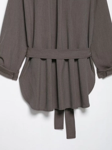 Détail de chemise gris foncé à manches longues avec ceinture et ourlet arrondi élégant