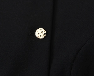 Dettaglio del tessuto in twill nero con un bottone in metallo dorato irregolare pregiato