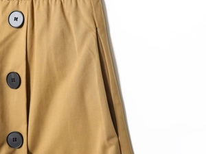 Dettaglio del tessuto twill kaki con bottoni neri e tasca laterale su una gonna-pantalone
