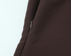 Détail macro de la fermeture éclair invisible et du tissu marron foncé du haut femme