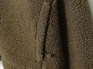 Detailed macro view of olive green teddy fleece fabric and woven strap on soft sweater