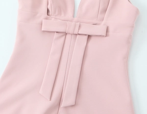 Detailed view of pink short dress featuring decorative bow and vertical ribbon accents