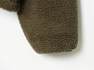 Close-up of olive green Sherpa fleece fabric showing thick and soft granular texture