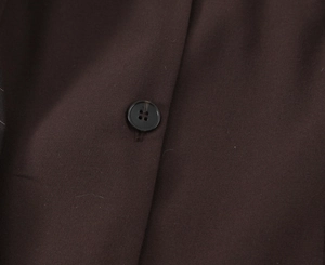 Détail du tissu de robe sans manches marron foncé avec un bouton noir à quatre trous