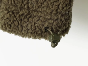 Detailed close-up of dark olive green teddy fleece texture with adjustable drawstring toggle