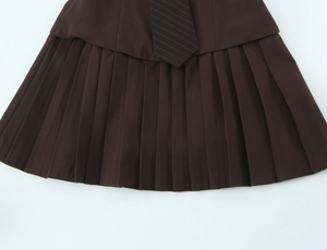 Détail d'une robe plissée marron foncé avec accessoire de cravate à rayures diagonales