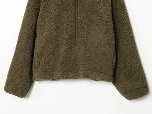 Detail view of olive green teddy fleece texture and hidden side pocket on the sweatshirt