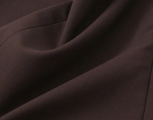 Gros plan sur la texture du tissu textile marron foncé de qualité avec un drapé élégant