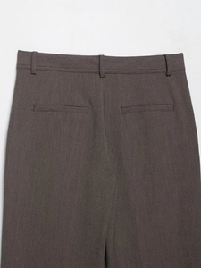 Détail du pantalon droit montrant les poches arrière passepoilées et le tissu texturé