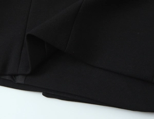 Dettaglio del tessuto nero e cuciture precise sull'orlo di una giacca da blazer