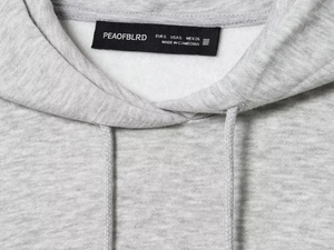 Detail des grauen Kapuzenpullover-Ausschnitts mit Kordelzug, Markenetikett und Struktur