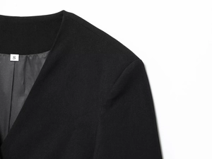 Detail of black blazer collar and shoulder with a size S woven label on the inner lining