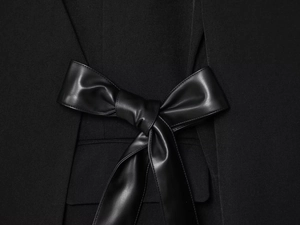 Detailed view of an elegant oversized black leather bow on a premium wool blazer jacket