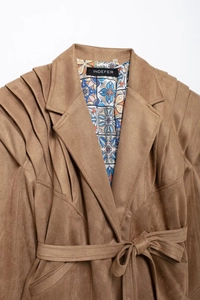 Detailed close-up of brown suede jacket featuring pleated ruffle shoulders and floral lining