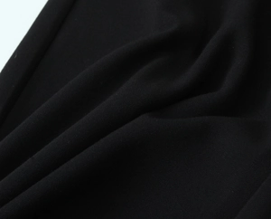Dettaglio macro del tessuto nero strutturato per un elegante completo da donna