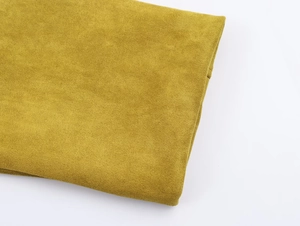 Gros plan sur la texture en daim vert olive et les finitions douces de la veste