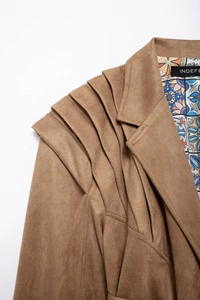 Detail of dark brown faux suede jacket featuring tiered shoulder pleats and geometric lining