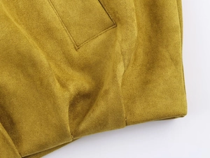 Gros plan détaillé du tissu en daim jaune moutarde et des coutures de la poche