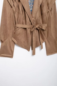 Detail of faux suede jacket with belted waist and bohemian floral pattern lining