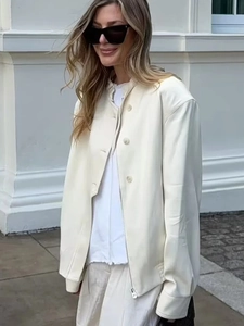 Detail of cream white faux leather jacket featuring button closure and stand collar design