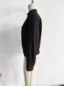 Detailed side view of black minimalist jacket with stand collar and ribbed hem