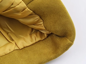 Détail macro du tissu suédé moutarde avec doublure en satin doré sur un blouson bomber
