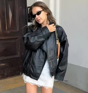 Street style shot of a black faux leather jacket with stand collar and zipper closure