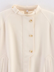 Detail of cream buttoned jacket with stand collar and tortoise shell buttons