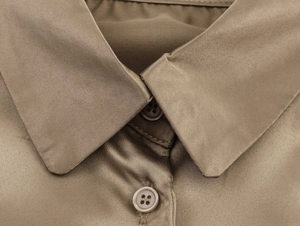 Macro detail of bronzed satin shirt featuring classic collar and matching buttons