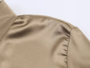 Detailed close-up of champagne satin blouse showing shoulder seams and silky fabric texture