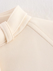 Detailed macro view of the cream textured fabric and stitching on the collar of the jacket