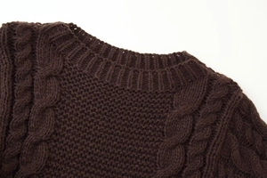 Detail of dark brown cable knit sweater showing rib-knit crewneck and thick wool texture