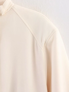 Detailed view of beige jacket shoulder seam with high-quality textured woven fabric