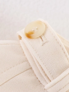 Detailed close-up of amber textured button and fine stitching on beige jacket fabric