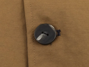 Detailed close-up of marble texture button on khaki twill jacket fabric
