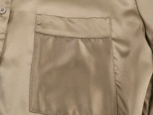 Detail of champagne satin shirt showing smooth fabric texture and a neat square pocket