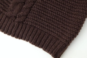 Close-up of cable knit texture and ribbed hem on a dark brown long sleeve sweater