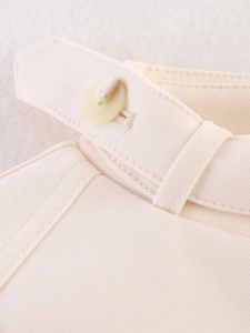 Macro detail of high-quality cream twill fabric with precision stitching and matching button