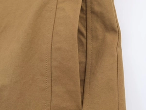 Close-up of khaki trench coat fabric showing twill weave texture and side pocket stitching