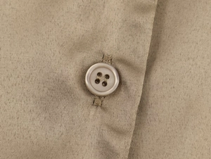 Close-up of khaki twill fabric detail with a round resin button and precise buttonhole