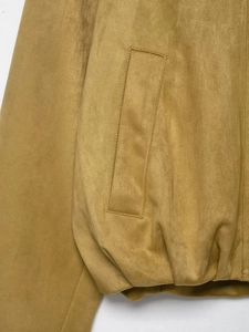 Détail macro du blouson aviateur en suédine camel montrant la couture de la poche