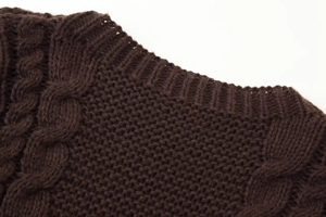 Detail of cable knit pattern and ribbed crew neck on dark brown textured sweater