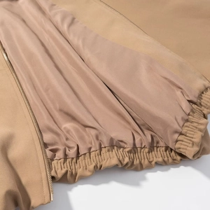Detail einer khakifarbenen Kurzjacke mit Metallreißverschluss und Innenfutter