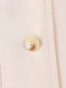 Detailed macro view of the marble-textured button and beige twill fabric texture